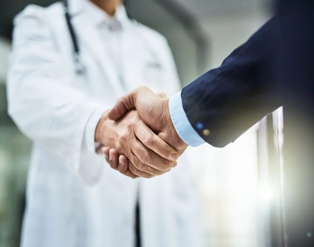 A physician and business professional shake hands.