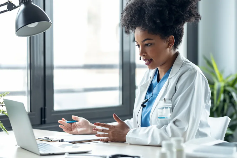 Clinician using a laptop and headset for a remote consultation