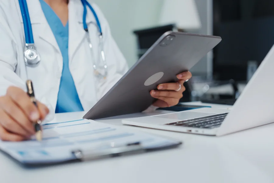 A clinician reviewing practice documents alongside a tablet